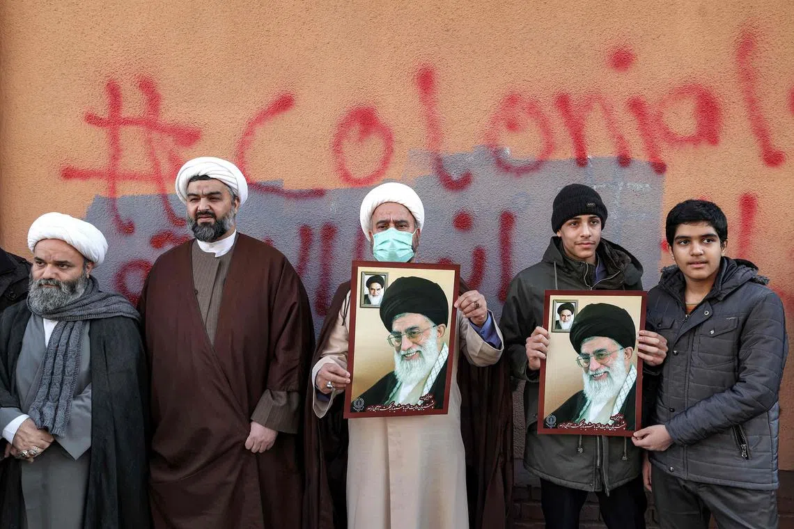 TOPSHOT - Demonstrators gather with images of Iran's supreme leader Ayatollah Ali Khamenei during a protest against defamatory cartoons depicting him published by French satirical weekly Charlie Hebdo, outside the French embassy in Iran's capital Tehran on January 8, 2023. (Photo by ATTA KENARE / AFP)