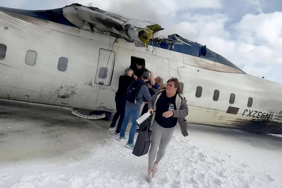 Passengers leaving the Delta Air Lines regional jet after it landed and turned over at the Toronto Pearson International Airport on Feb 17.