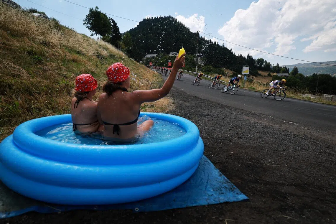Cycling - Tour de France - Stage 10 - Aurillac to Le Lioran - Aurillac, France - July 14, 2026
Lidl - Trek's Quinn Simmons and other cyclists in action as spectators in an inflatable water tub cheer on during stage 10 REUTERS/Stephanie Lecocq     TPX IMAGES OF THE DAY