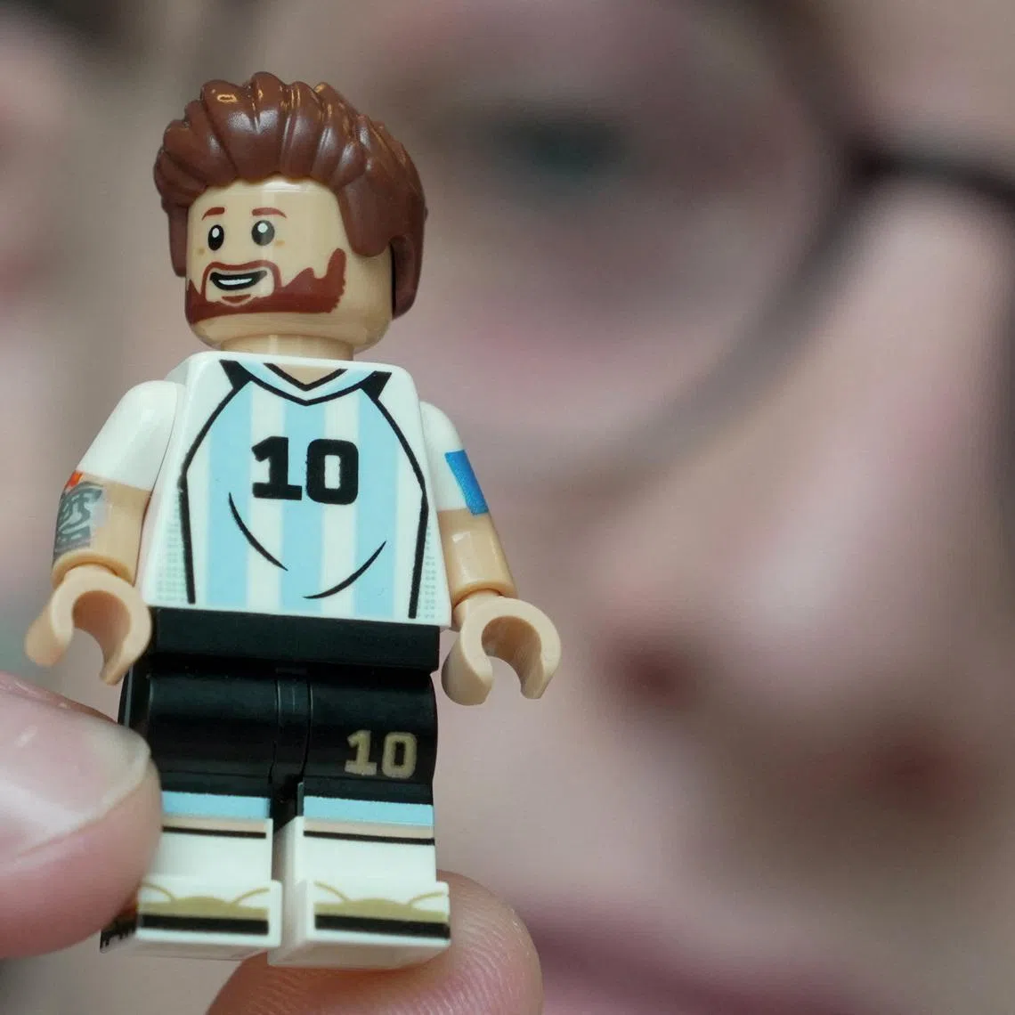 LEGO model designer Freddy Charters holds up a minifigure of Lionel Messi in Billund, Denmark, March 27, 2026. REUTERS/Tom Little
