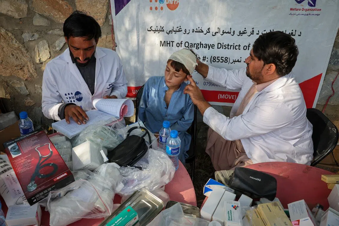 A doctor examines a victim of a deadly magnitude-6 earthquake that struck Afghanistan on Sunday, at a mobile clinic setup inside a school, in Nurgal district, Kunar province, Afghanistan, September 3, 2025. REUTERS/Sayed Hassib