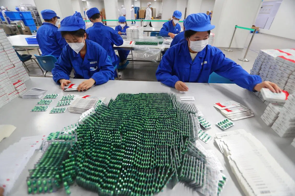 Workers pack medicine to treat Vovid-19 symptoms at a factory in Beijing on Dec 11, 2022. 