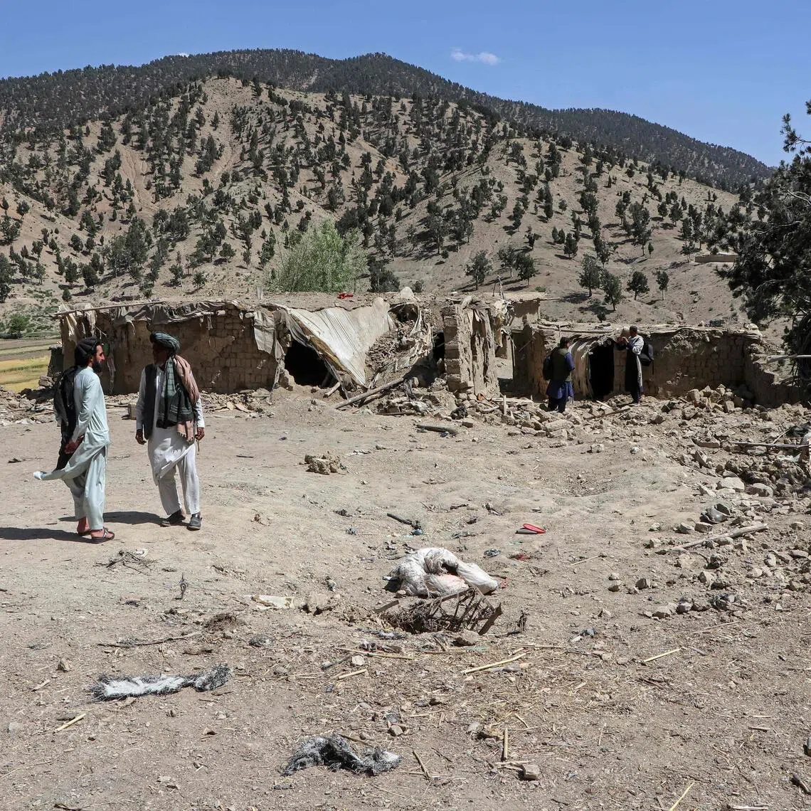 Afghan residents stand near a damaged house after a Pakistan airstrike in the Barmal district of Paktika province on June 10.