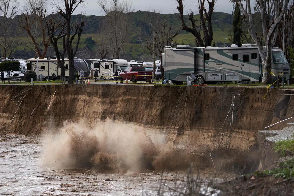 A large tree falls as the Santa Clara River floods due to heavy rain washing away over 150 feet of land and multiple rv homes in Castaic, California, on Feb 25.
