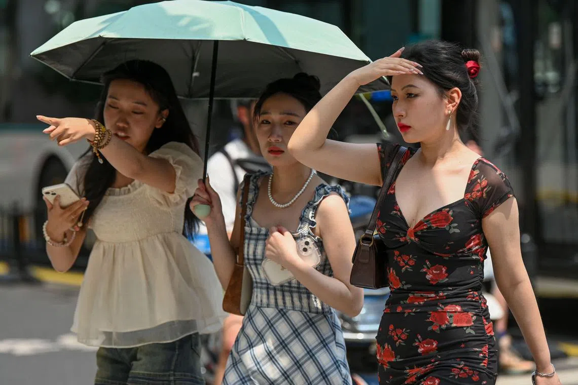 (FILES) Women use an umbrella to shelter from the sun amid hot weather in Shanghai on May 29, 2023. Heatwaves across Asia and beyond have already broken records this year, while the arrival of the El Nino climate phenomenon will mean even more extreme temperatures (Photo by AFP) / China OUT