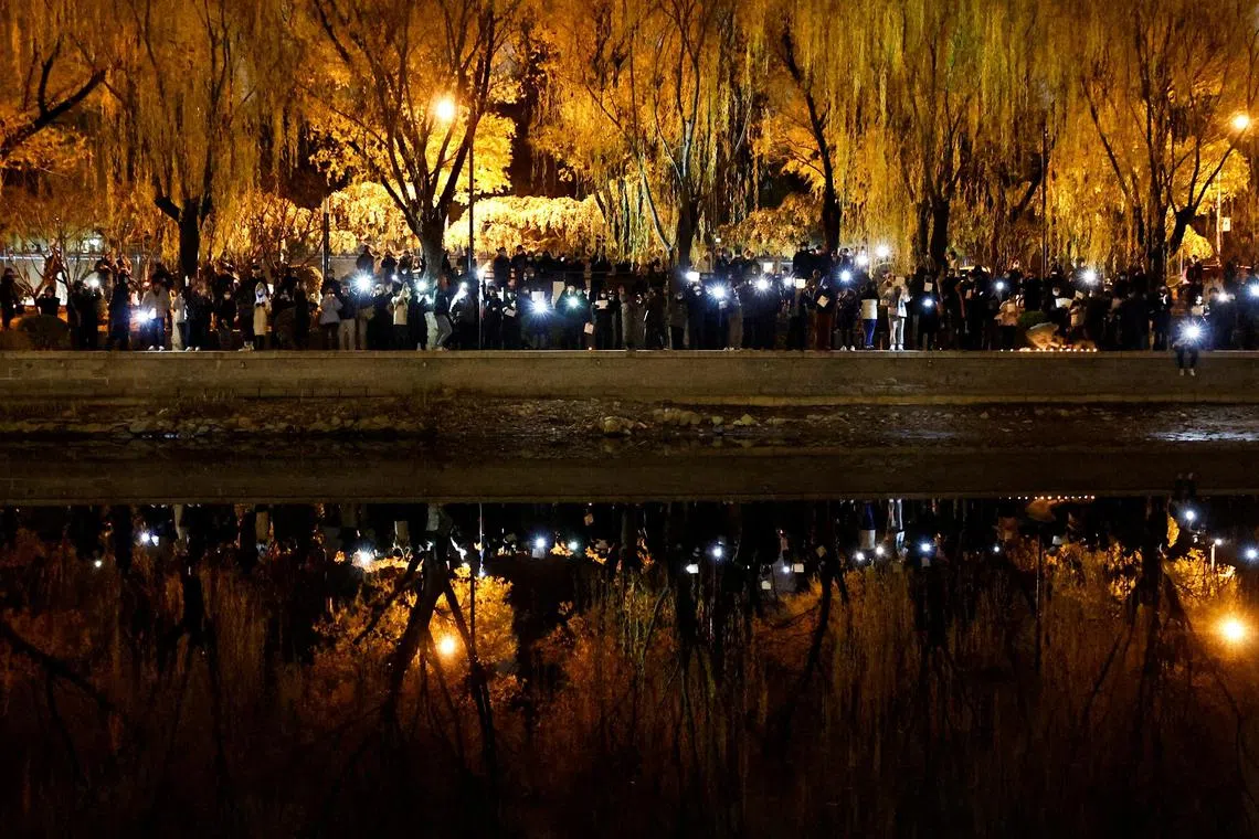 FILE PHOTO: People gather for a vigil and hold white sheets of paper in protest of coronavirus disease (COVID-19) restrictions, as they commemorate the victims of a fire in Urumqi, as outbreaks of the coronavirus disease continue in Beijing, China, November 27, 2022. REUTERS/Thomas Peter/File Photo