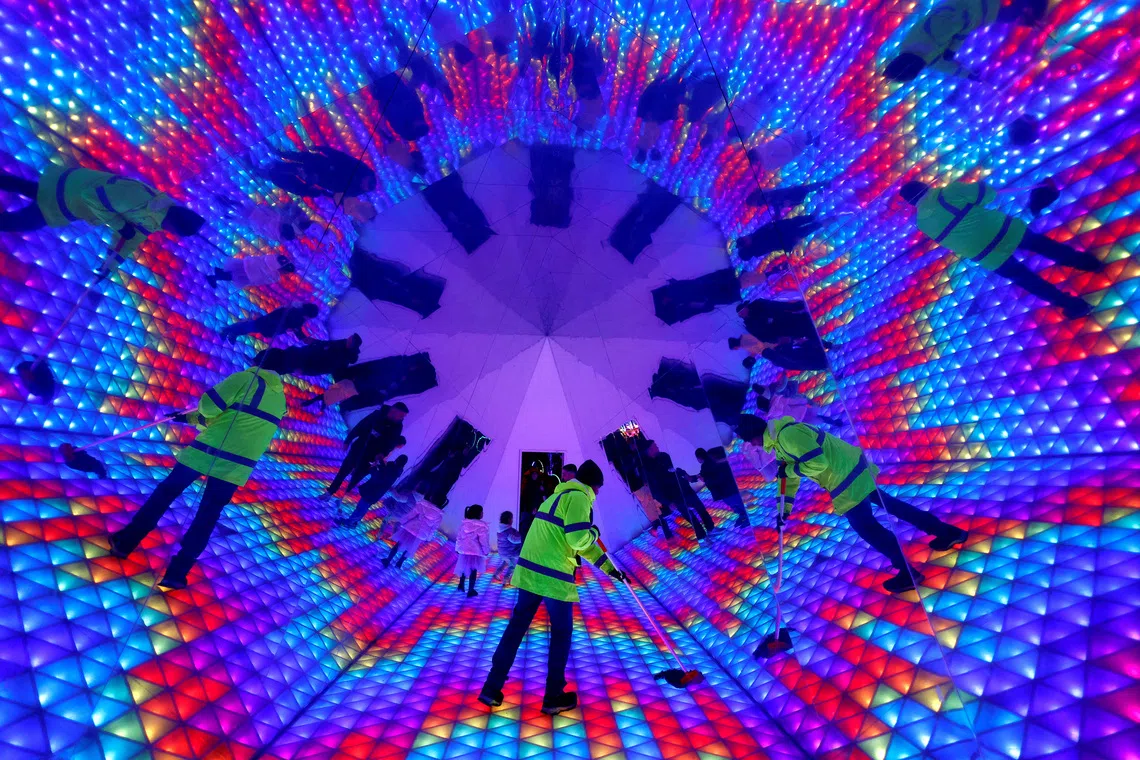 A worker mopping the floor inside a kaleidoscope tunnel at a winter lights Christmas installation, in Dublin, Ireland, on Dec 3, 2025. 
