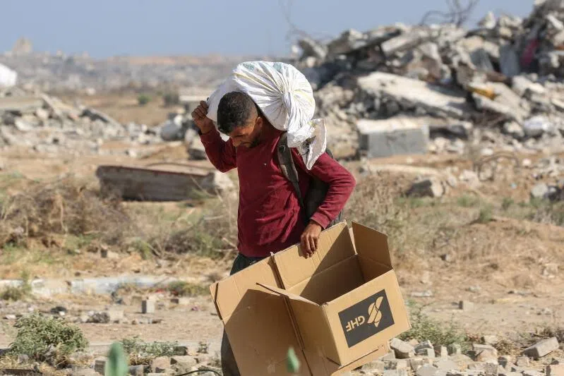 A Palestinian man walks with a bag of humanitarian aid received at a distribution centre run by the Gaza Humanitarian Foundation in Nuseirat, Gaza.