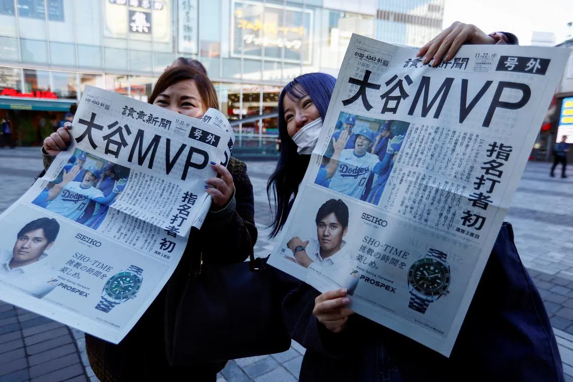 People celebrate as they receive extra editions of a newspaper reporting Japan's Shohei Ohtani of the Los Angeles Dodgers was named Most Valuable Player of Major League Baseball's National League in Tokyo, Japan Japan November 22, 2024. REUTERS/Issei Kato