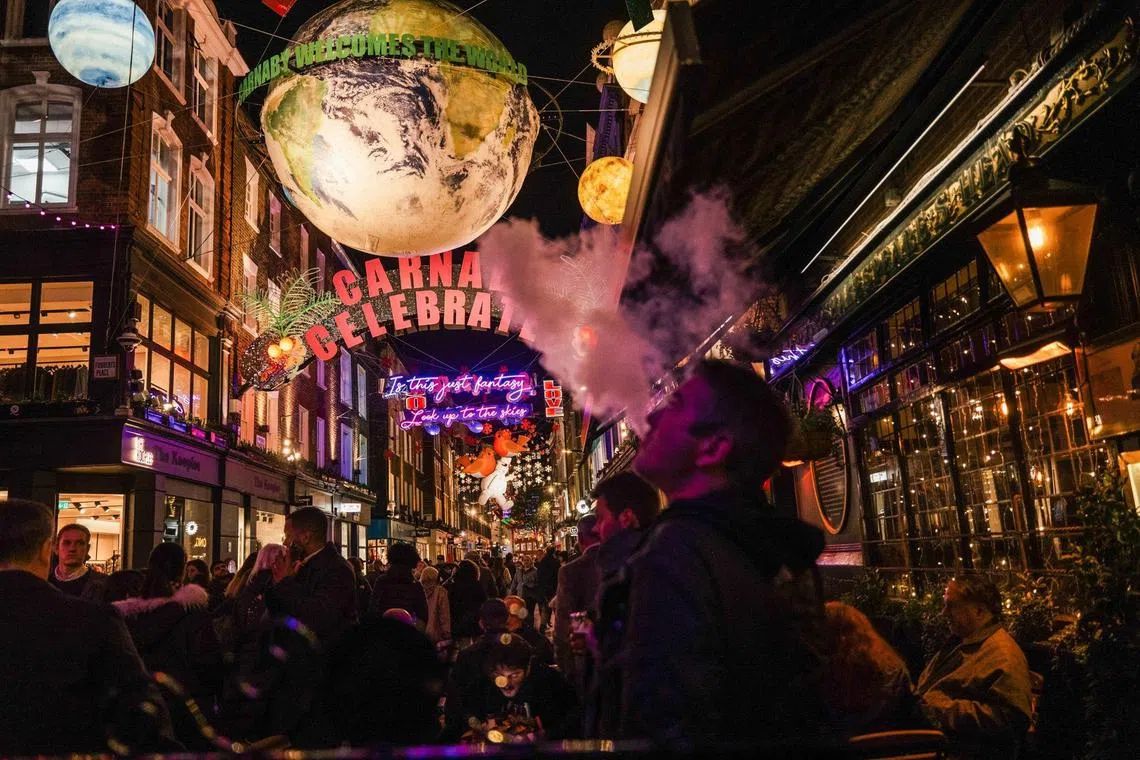 A customer smokes an electronic cigarette outside a pub on Carnaby Street in the Soho district of London, UK, on Wednesday, Nov. 23, 2022. The famous Christmas lights on London’s Oxford Street will use two-thirds less energy this year by reducing operating times to 8 hours a day and switching to LED lighting, according to the New West End Company, which organizes the display. Photographer: Jose Sarmento Matos/Bloomberg