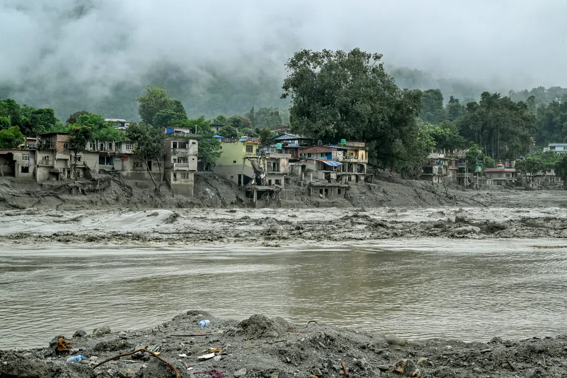 Houses destroyed by flash flooding stand next to a swollen river in Devighat, Nepal, on Aug 30.