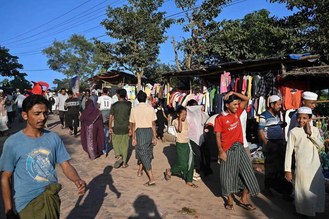 This photograph taken on Dec 18, 2025 shows Rohingya refugees walking along a market at the Kutupalong refugee camp in Bangladesh's Ukhia.