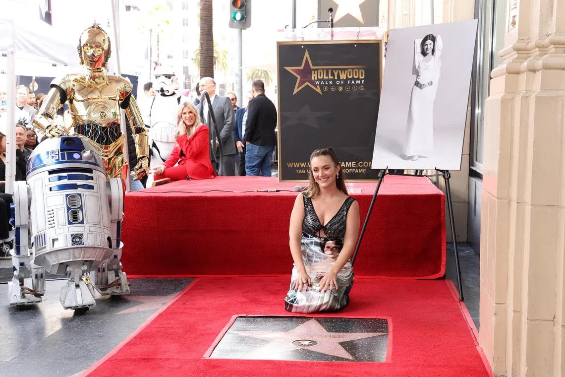 Billie Lourd poses with the star of actor Carrie Fisher next to Star Wars characters C-3PO and R2-D2 during its posthumous unveiling ceremony on the Hollywood Walk of Fame in Los Angeles on May 4, 2023. 