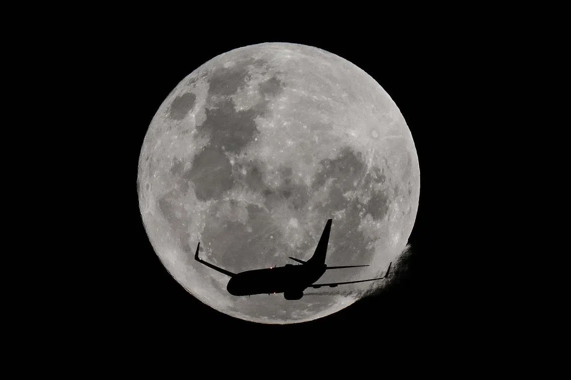 An aircraft passing in front of the full moon, known as the 'Strawberry Moon', over Coogee Beach in Sydney on June 11, 2025. 