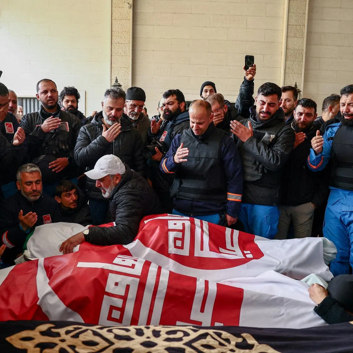 People mourn over the bodies of two paramedics killed by an Israeli strike, amid escalating hostilities between Israel and Hezbollah, as the U.S.-Israeli conflict with Iran continues, in Nabatieh, Lebanon, March 25, 2026. REUTERS/Yara Nardi