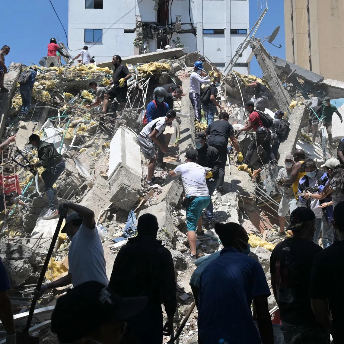 TOPSHOT - People look for survivors amid the rubble of a collapsed building after an earthquake in Cali, Colombia, on August 10, 2026. A powerful earthquake rocked Colombia and neighboring Latin American countries on August 10, 2026, with medical teams rushing to help victims after buildings were damaged or collapsed in several cities. The Colombian geological service and its American counterpart USGS put the magnitude at 7.4, with an epicenter 100 km (60 miles) underground in the west of the country. Colombia had initially put it at 6.6. (Photo by Joaquín SARMIENTO / AFP)