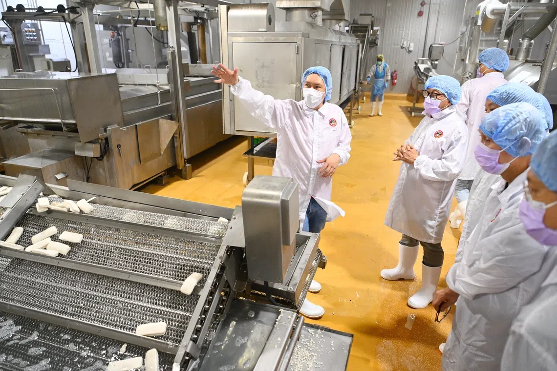 Thong Siek Global's brand manager Erik Lee (left) explaining to visitors on Sept 5 how surimi is turned into the food manufacturer's popular items like fish cake.