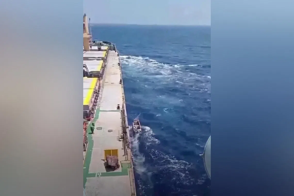 A boat sails next to a shipping vessel MV Abdullah in this screengrab obtained from a social media video released on March 12, 2024. 