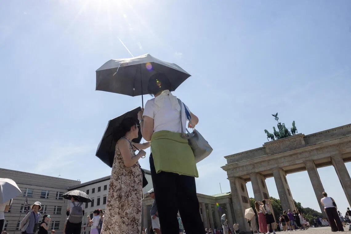 People shielding themselves from the sun as they stand in front of Germany’s Brandenburg Gate during a heatwave in June 2026. Germany baked in temperatures of over 40 deg C in late June.