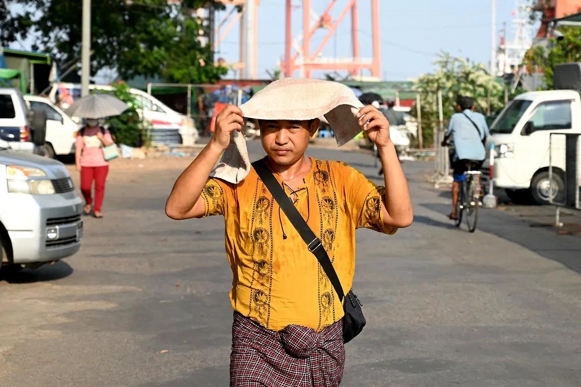 A man covers his head with a towel to shelter from the sun during a heatwave in Yangon, Myanmar, on May 8, 2023. 