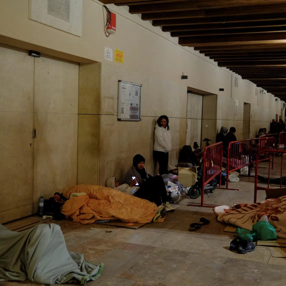 People rest as they wait in a queue in the early morning to obtain a vulnerability certificate to regularise their migration status, at the town hall of Almeria, Spain, April 21, 2026. REUTERS/Nacho Doce