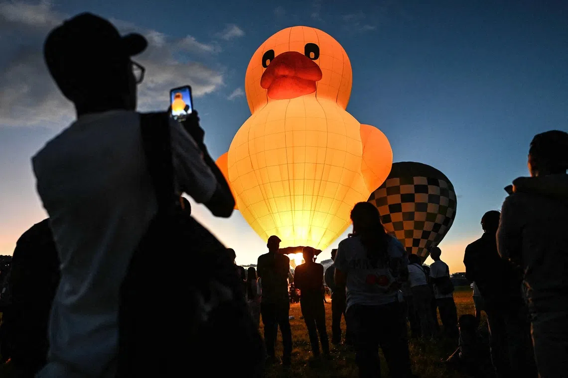A man taking a photo of a duck-shaped hot air balloon during the Expo Transporte event at Francisco de Miranda Air Base in Caracas, on Dec 7, 2025. 