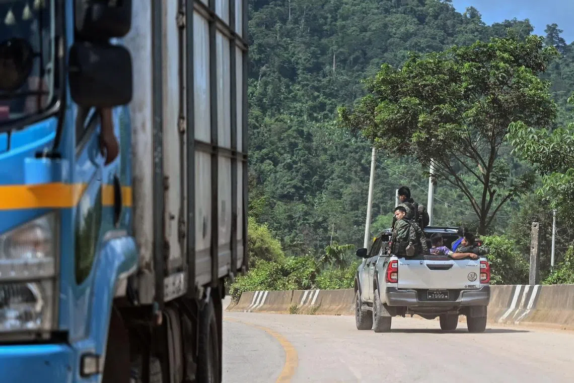 This photo taken on September 24, 2023 shows members of the Karen state Border Guard Forces (BGF) patrolling on the Yangon-Myawaddy section of the Asia Highway road near Kawkareik township. The Myadawady-Yangon section of the Asia Highway is just 400 kilometres long but snakes through rain-sodden, landslide-prone hills and its traffic obeys the rhythm of sporadic clashes between junta troops and their opponents. (Photo by AFP) / To go with 'MYANMAR-UNREST-TRANSPORT,FOCUS'