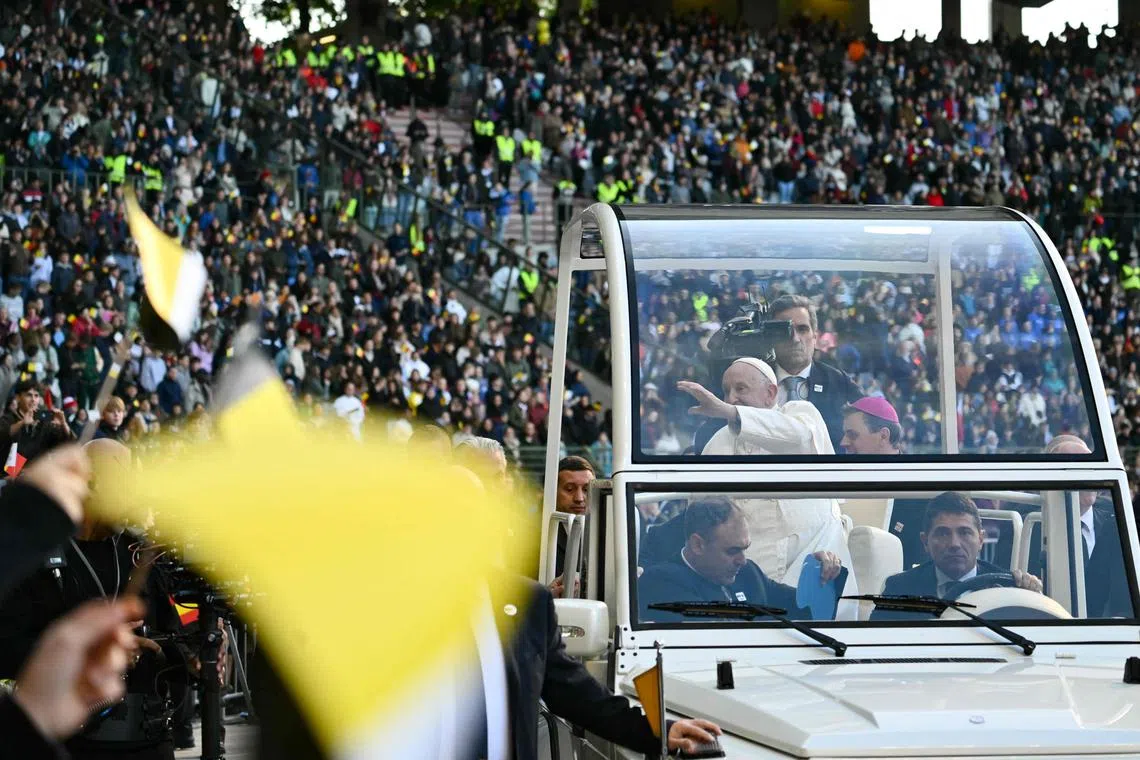 Pope Francis waves to the faithful as he arrives at King Badouin Stadium to hold a holy mass in Brussels on Sept 29.