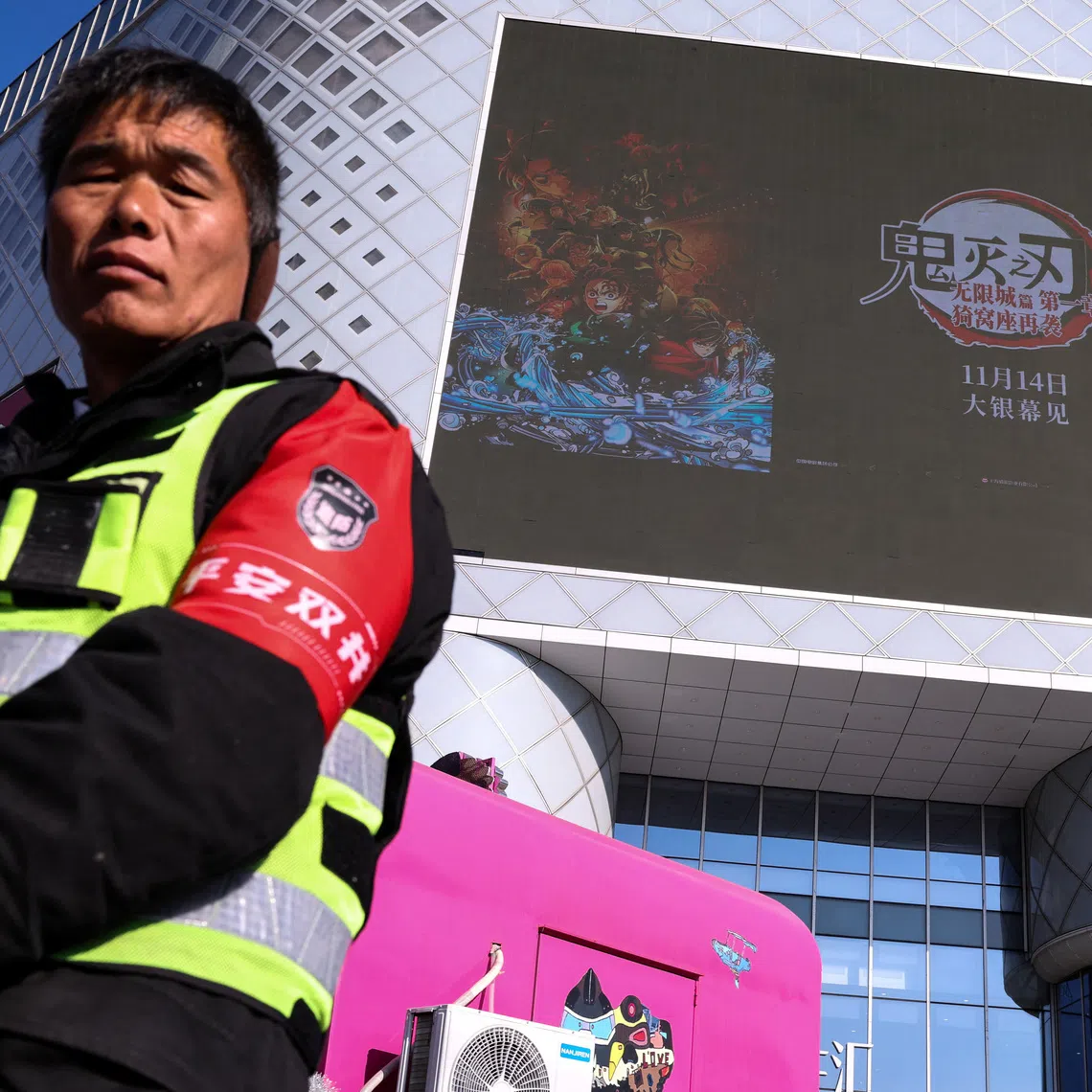 A security guard stands near a giant screen displaying a promotional video for the latest animated film in Japan’s Demon Slayer series on Nov 18.