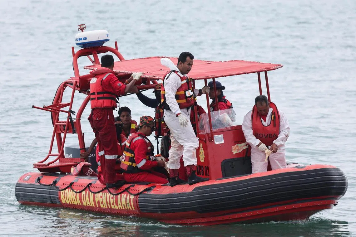 Rescuers carrying survivors from a vessel of refugees believed to be from Myanmar, which overturned in rough seas, in Langkawi on Nov 11.
