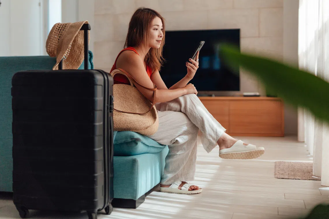 Best 9.9 sales in Singapore for travel deals: Young Asian woman with a luggage next to her getting ready for travel