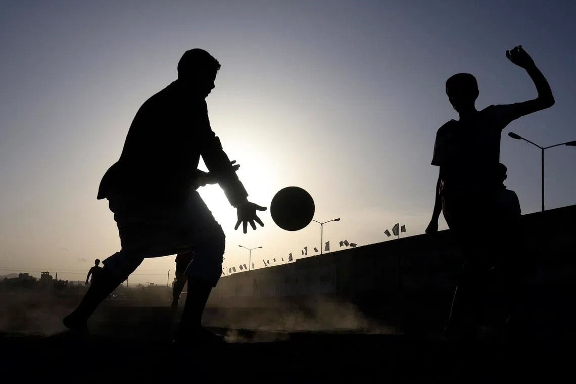 Silhouetted youths playing soccer on a dirt field during sunset in Sana'a, Yemen, on June 7, 2026. 