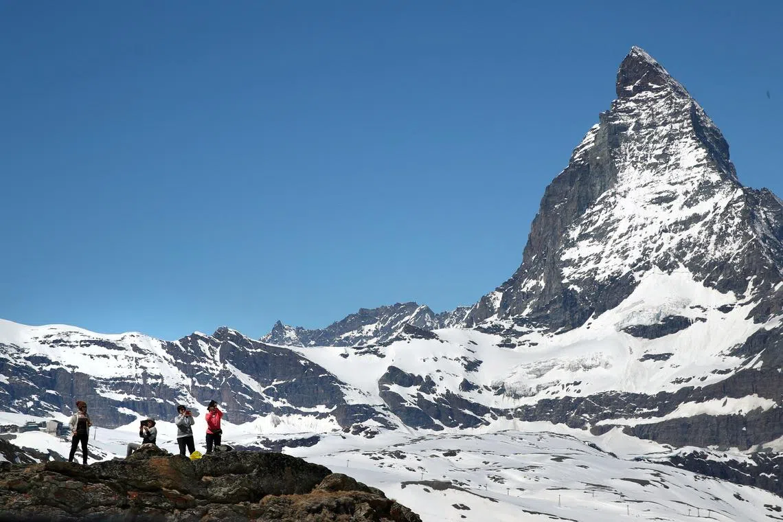 FILE PHOTO: Tourists take a picture in front of the Matterhorn mountain at the Gornergrat in Zermatt, Switzerland June 2, 2019. REUTERS/Denis Balibouse/File Photo
