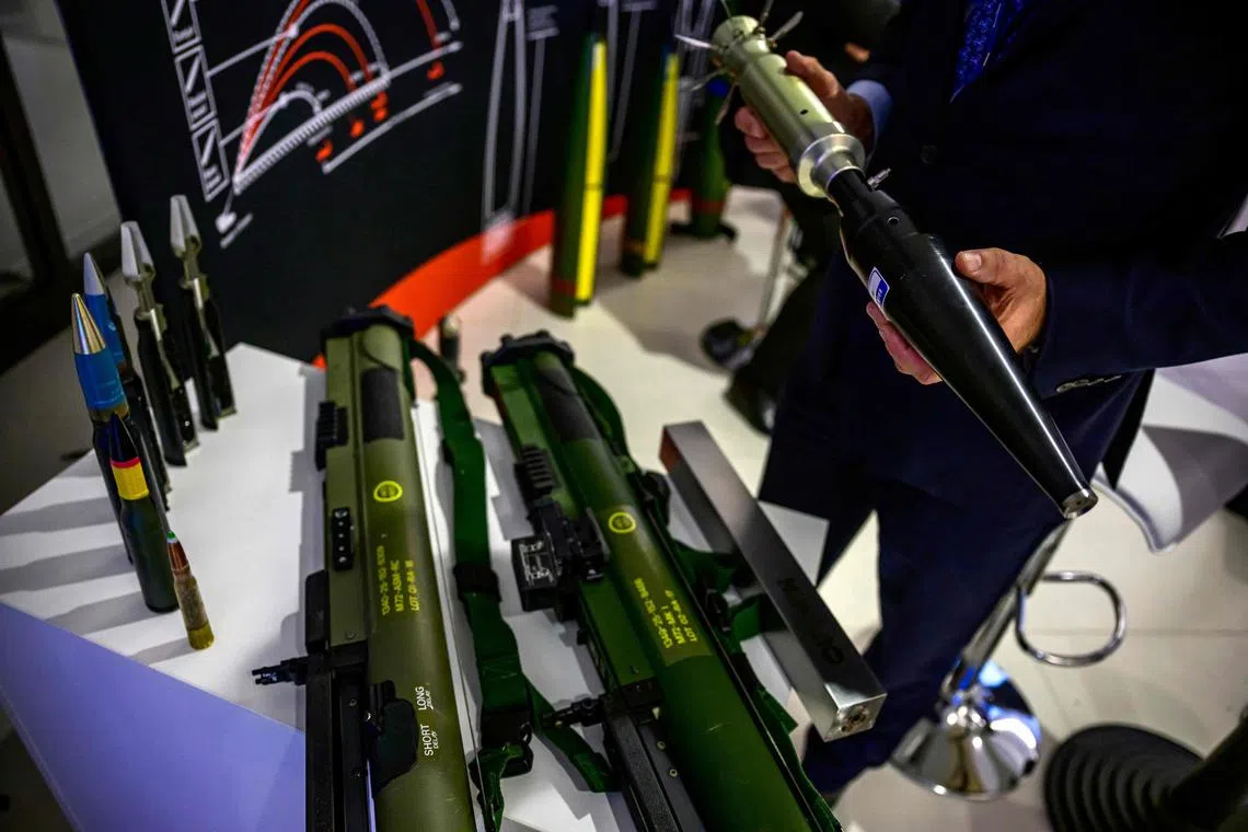 A consultant for Scandinavian arms manufacturer Nammo displays an anti-tank projectile for use with the M72 Shoulder-fired weapon on display at the Berlin Security Conference on European Security and Defence, on November 30, 2022 in Berlin. (Photo by John MACDOUGALL / AFP)