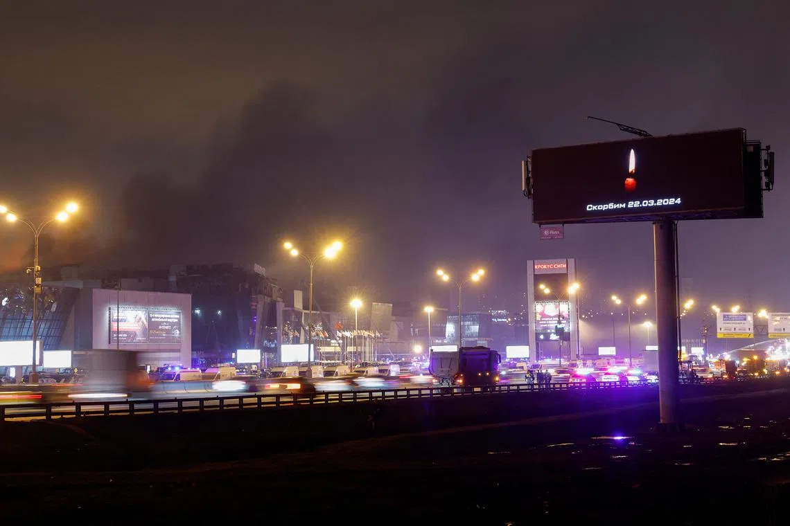 A digital board with a date and a slogan, that reads \"We mourn\" displayed in memory of victims of the shooting incident, is seen opposite the burning Crocus City Hall concert venue on the outskirts of Moscow, Russia, March 23, 2024. REUTERS/Maxim Shemetov