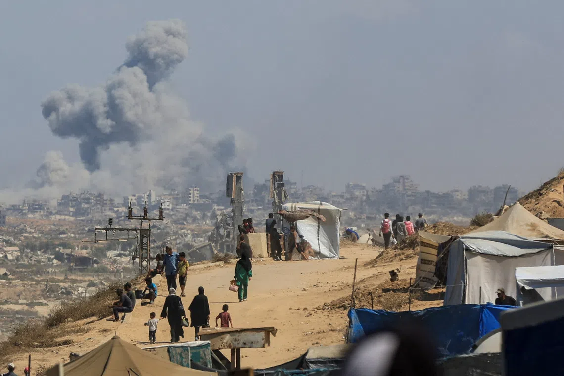 FILE PHOTO: Smoke rises from an Israeli strike, as displaced Palestinians, fleeing northern Gaza due to an Israeli military operation, move southward after Israeli forces ordered residents of Gaza City to evacuate to the south, in the central Gaza Strip September 24, 2025. REUTERS/Dawoud Abu Alkas/ File Photo