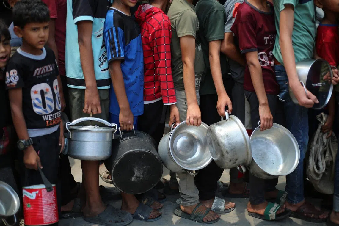 Palestinian boys queue at a hot meal distribution point in Nuseirat in the central Gaza Strip, on June 4.