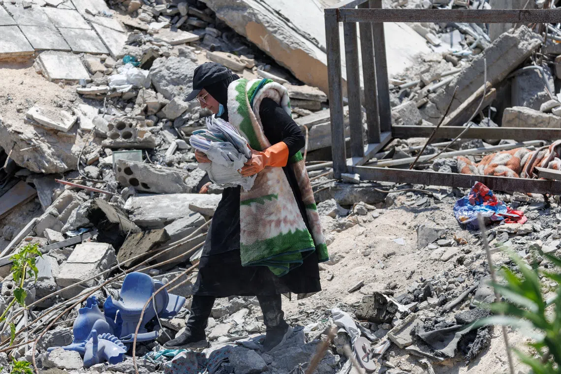 Nour Hamzeh carries her children's belongings salvaged from the rubble of her home, which was destroyed in an Israeli strike, after returning to Zawtar al-Gharbiyeh in southern Lebanon following the deployment of Lebanese soldiers in one of three so-called pilot zones established after the withdrawal of Israeli forces under a U.S.-brokered plan, July 27, 2026. REUTERS/Zohra Bensemra