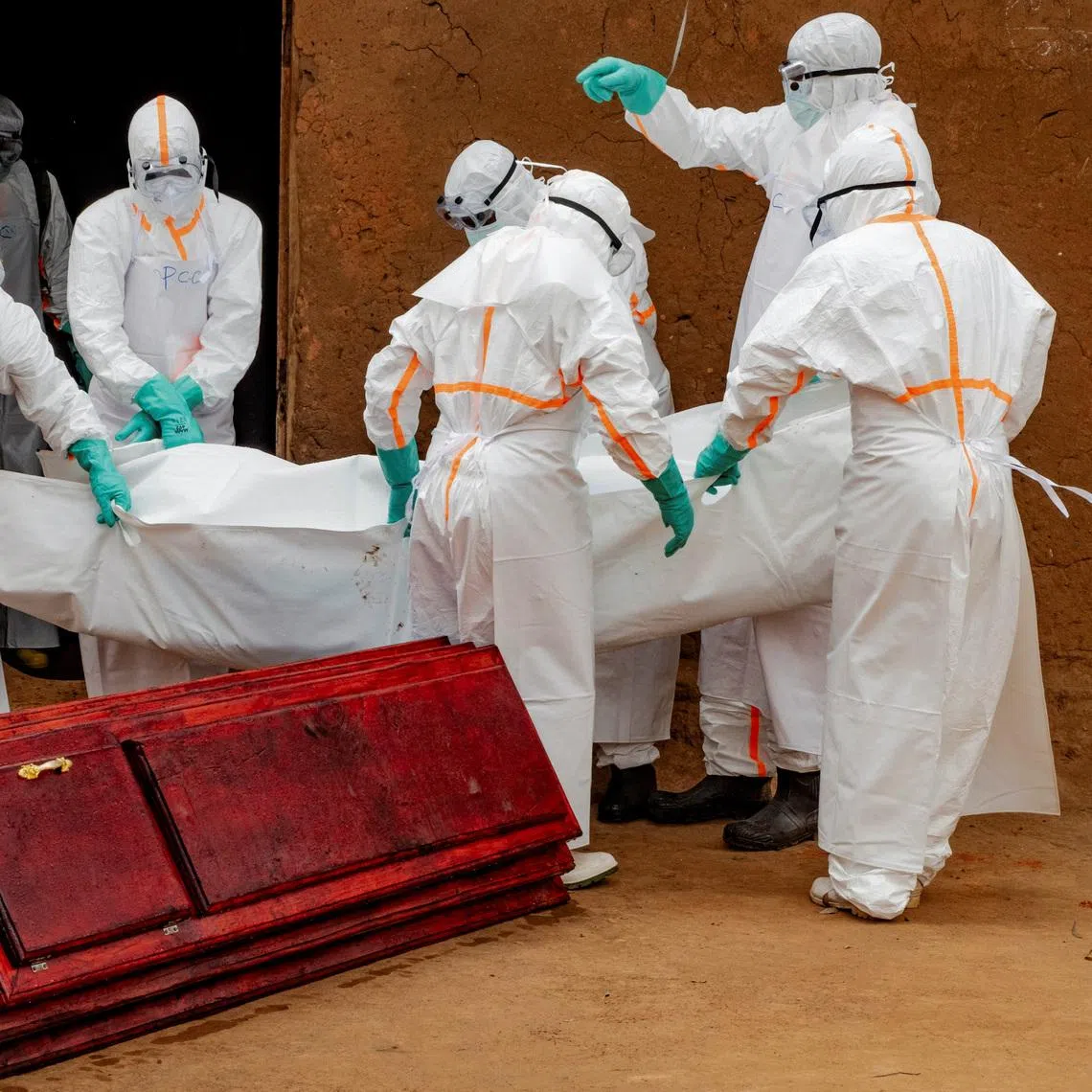 Members of the Civil Protection, a local community-based team that works to help mitigate the spread of the Ebola virus and ensure burials happen safely and quickly, wearing personal protective equipment (PPE), load in to a coffin the body of an unidentified man, who according to his family, died of Ebola, after retrieving it from his house, as aid agencies intensify efforts to contain a new Ebola outbreak involving the Bundibugyo strain, in Bunia, Ituri province, Democratic Republic of Congo, July 10, 2026. REUTERS/Gradel Muyisa Mumbere