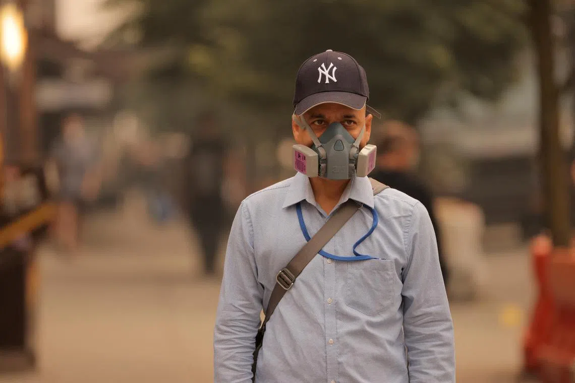 A man wearing a mask is seen walking by Long Island City in Queens as haze and smoke caused by wildfires in Canada hang over New York City on June 7, 2023. 