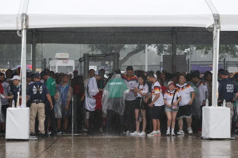 Fans seek shelter from the rain as they arrive before the FIFA World Cup 2026 Group E match between Germany and Curacao at Houston Stadium on June 14, 2026.