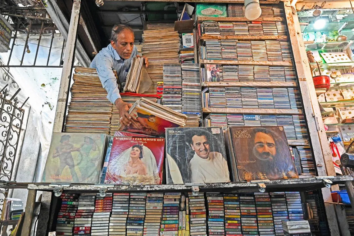 In this photograph taken on October 4, 2024, Royal Music Collection store owner Abdul Razzak, arranges vinyl records after opening his shop in Mumbai. Melting plastic pellets into chunky discs then squashed flat, a worker presses records in what claims to be the first vinyl plant to open in India in decades. The revival of retro records amongst Indian music fans mirrors a global trend that has seen vinyl sales explode from the United States to Britain and Brazil. (Photo by Indranil MUKHERJEE / AFP) / TO GO WITH 'India-Economy-Music' FOCUS