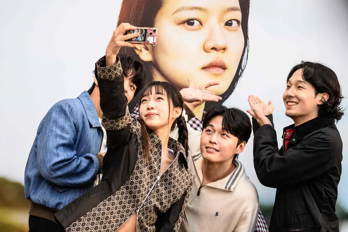 South Korean actors Joo Jong-hyuk (left) and Kim Woo-kyum (2nd from right) posing in front of a poster showing actress Go Ah-sung, for their film "Because I Hate Korea", during the 28th Busan International Film Festival (BIFF) in Busan on Oct 5.