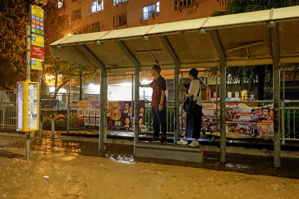 People waiting for the bus at a flooded area during heavy rain in Hong Kong, China, Sept 8, 2023. 