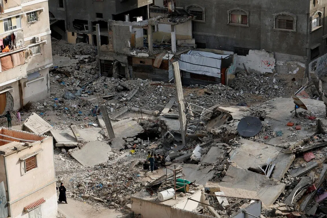 A Palestinian woman walks near the rubble of houses, in Khan Younis in the southern Gaza Strip March 29, 2025. REUTERS/Hatem Khaled