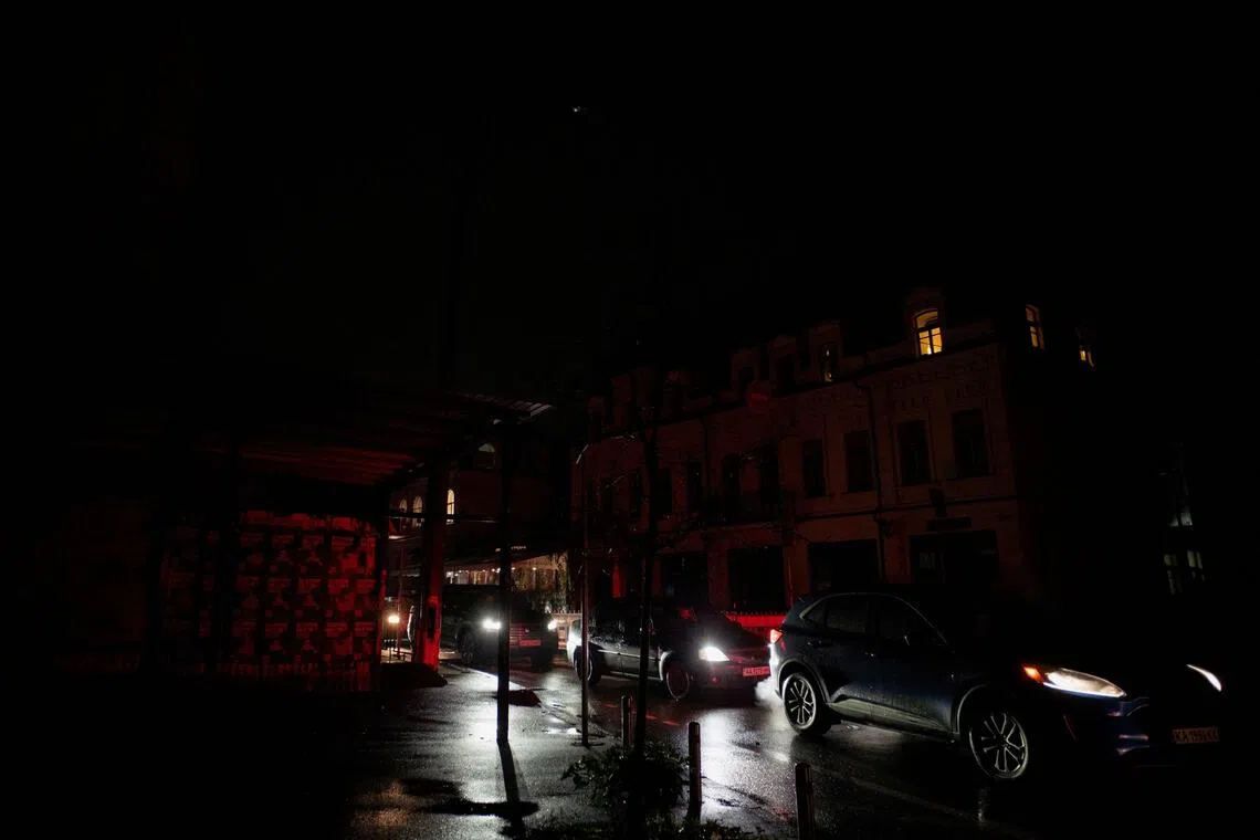 Commuters drive their vehicles on a non-illuminated street during blackout hours in Kyiv on Nov 21.