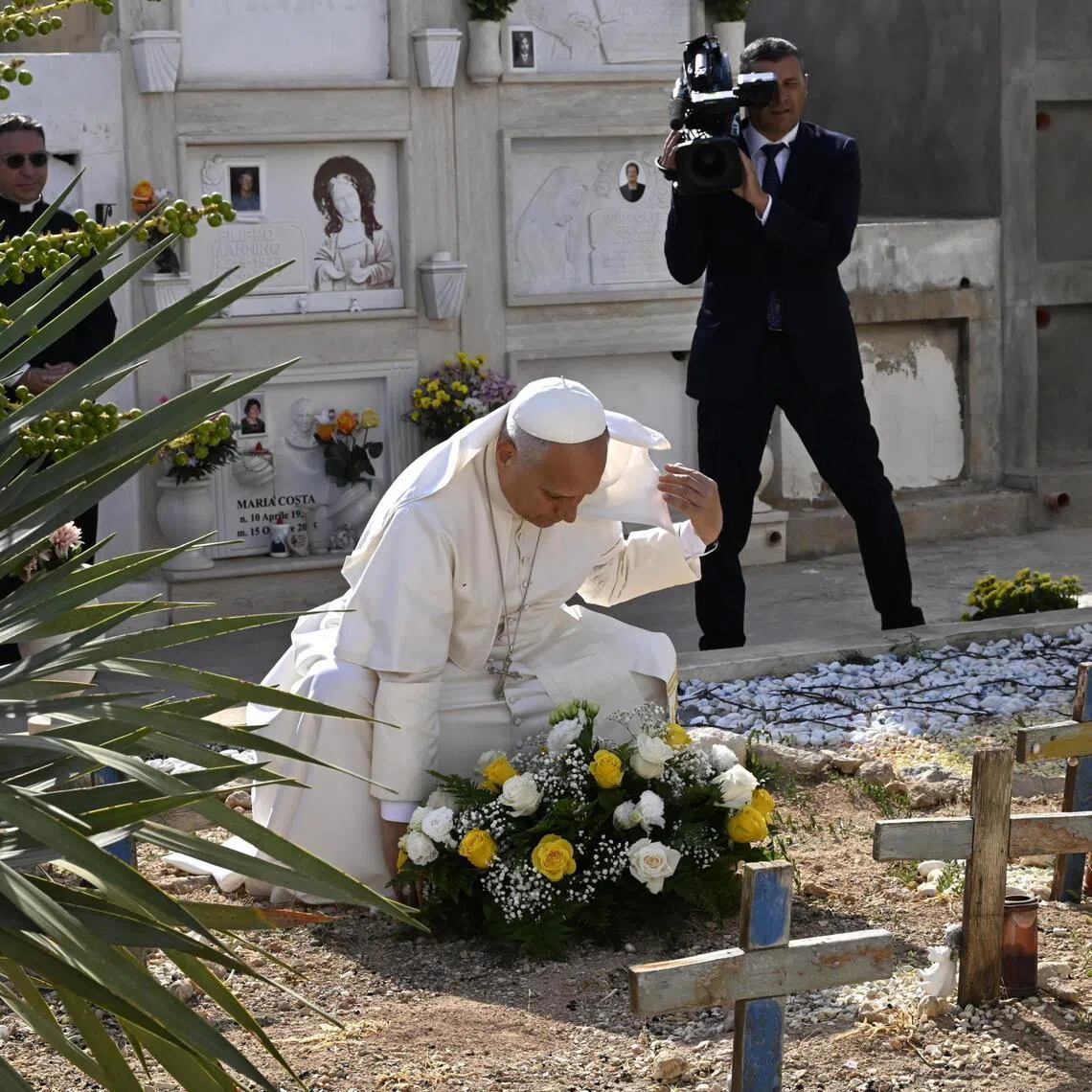 Pope Leo XIV lays a floral tribute on a grave during his stop at a local cemetery as part of his pastoral visit to the island of Lampedusa, in southern Italy, on July 4.