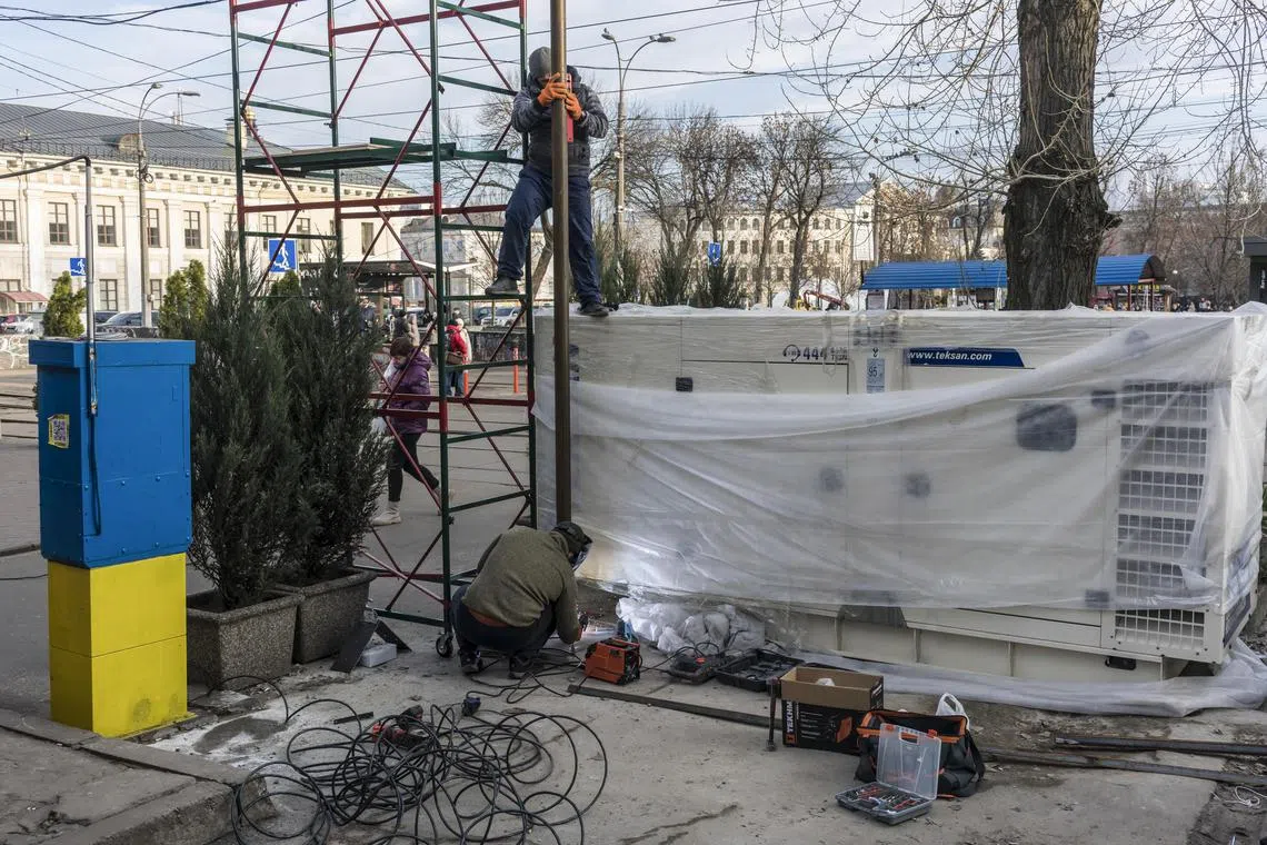 Workers install a generator to provide electricity to a nearby office building in Kyiv, Ukraine, on Jan 3, 2023.