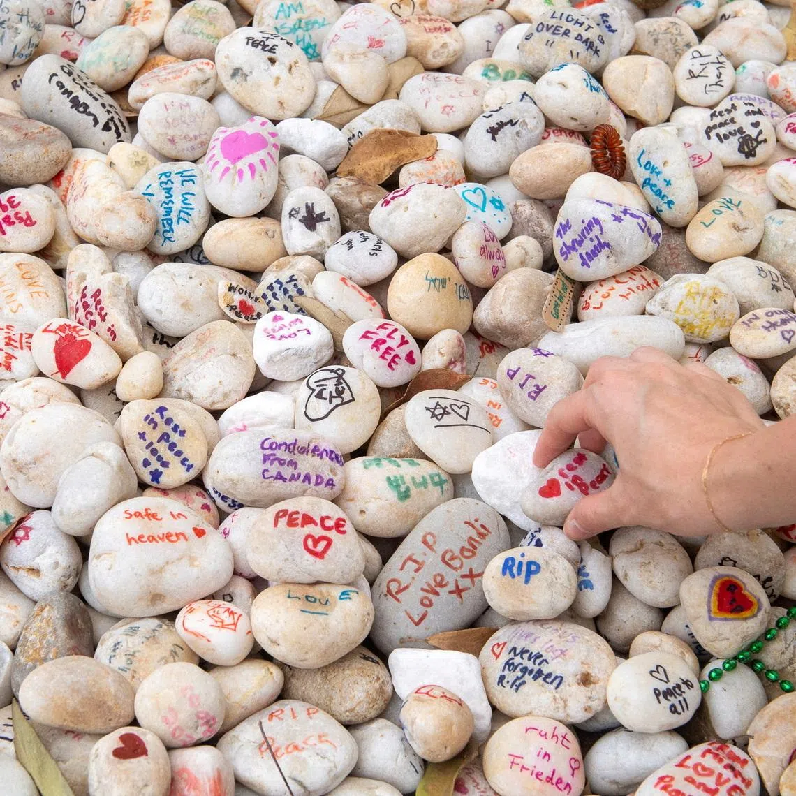 A visitor places a pebble at a memorial site in remembrance to the lives lost during the Bondi Beach mass shooting on December 14, 2025, in Sydney, Australia. REUTERS/Jeremy Piper
