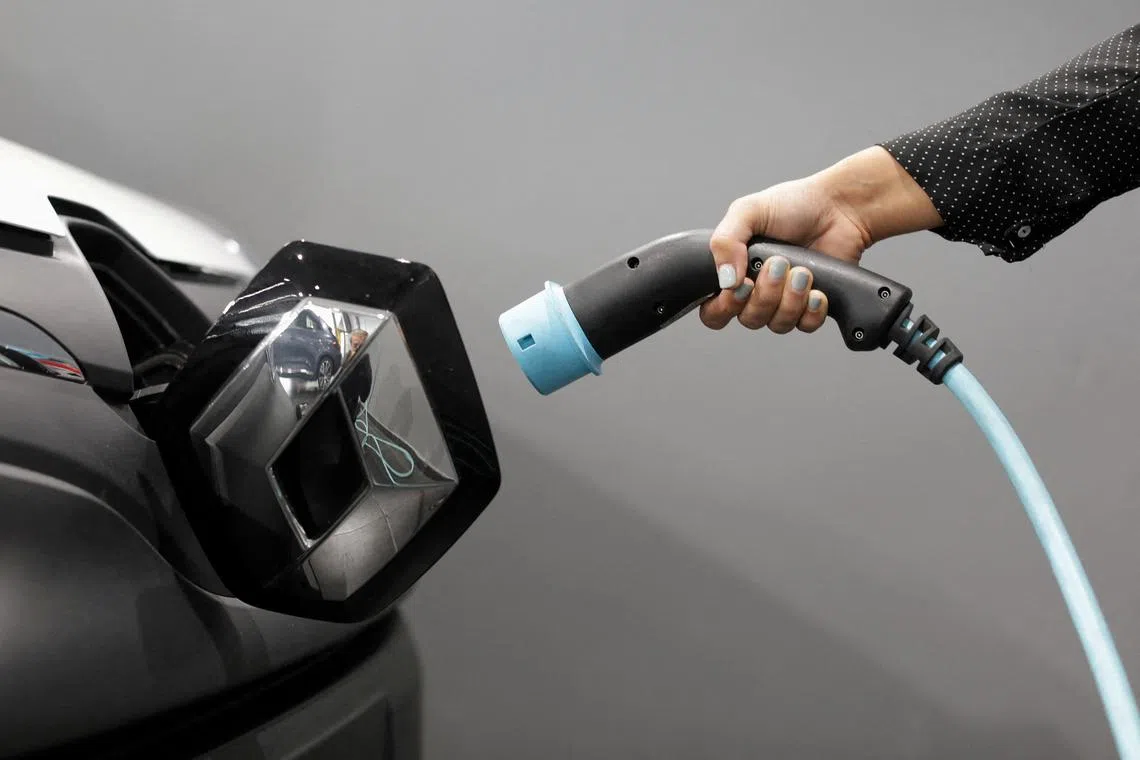 A woman holds a cable to charge a Renault Kangoo ZE electric utility vehicle at a Renault automobile dealership in Cagnes-Sur-Mer, France. The company is preparing the EV and software entity for a potential initial public offering in Paris next year.